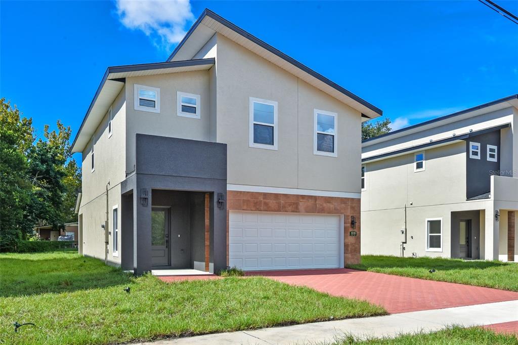 A two-story modern house with a beige facade, dark gray entryway, and a red driveway — 1030 WILKS AVENUE, ORLANDO, FL