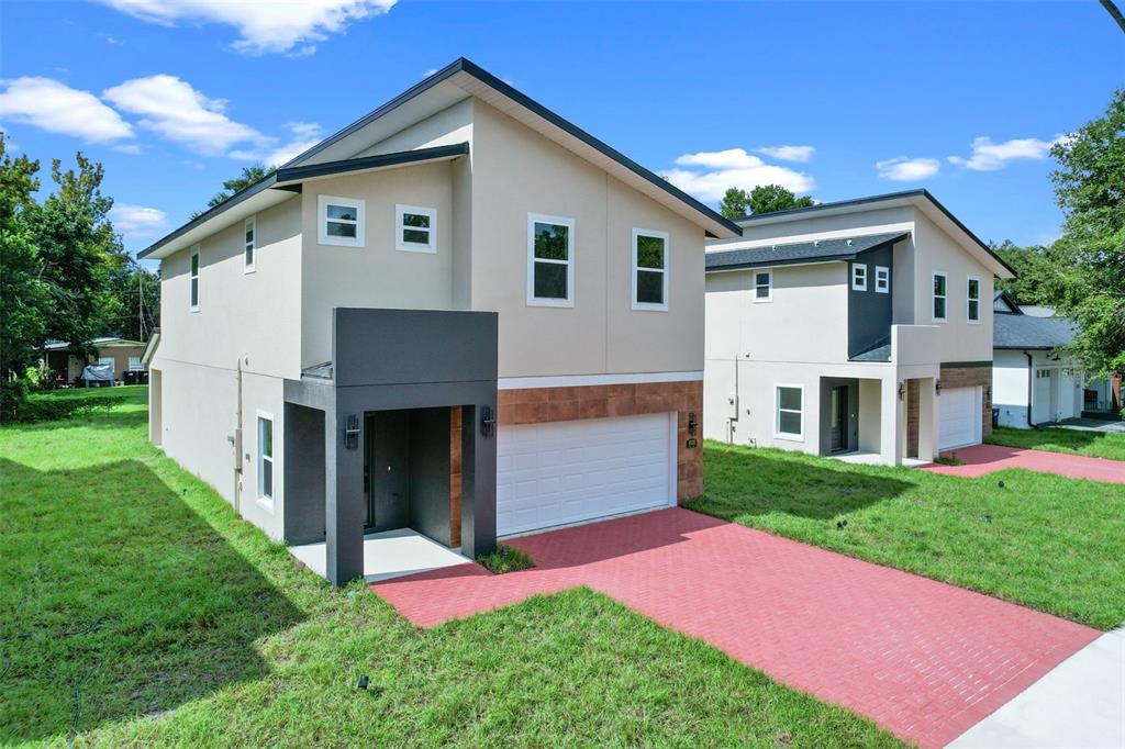 Two modern two-story houses with beige stucco, dark accents, and red brick driveways — 1030 WILKS AVENUE, ORLANDO, FL