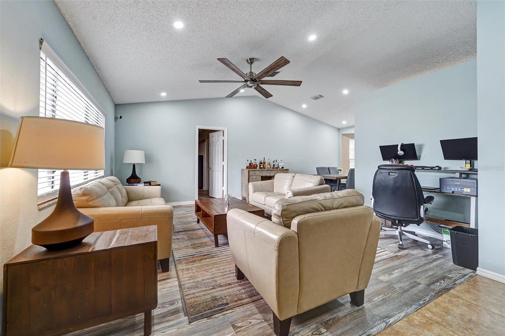 A living room with light blue walls, beige leather furniture, and a wood-look floor — 1250 FINLAND DRIVE, SPRING HILL, FL