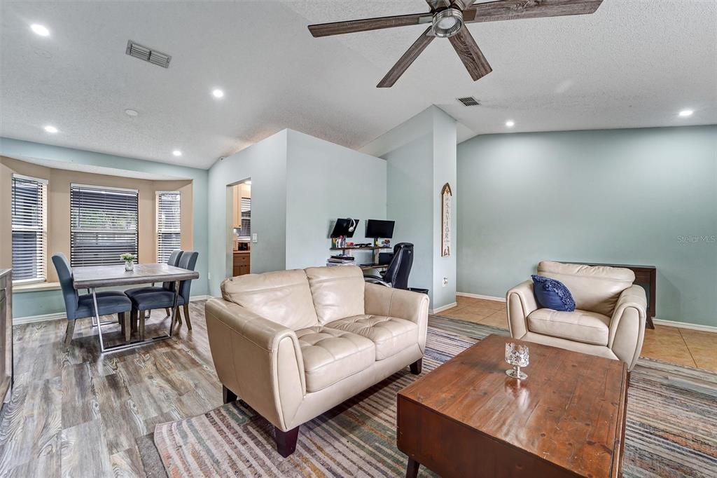 A living room features a beige sofa, matching armchair, wood coffee table, and dining area — 1250 FINLAND DRIVE, SPRING HILL, FL