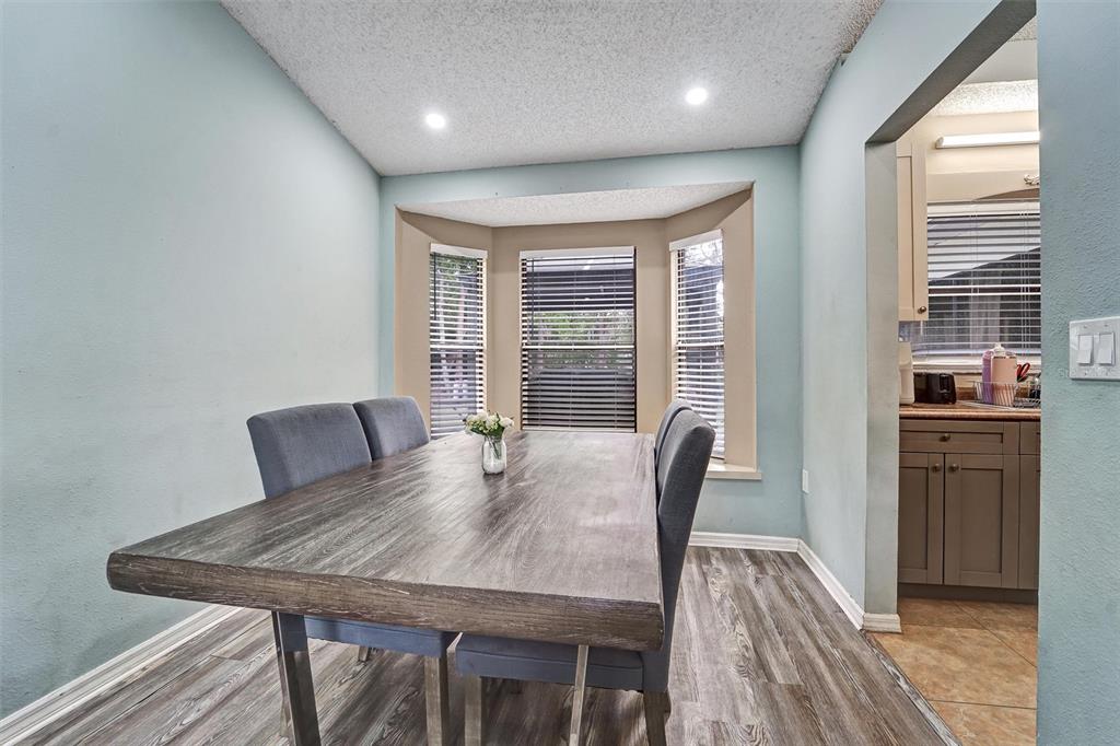A dining area features a wooden table, gray upholstered chairs, and a bay window — 1250 FINLAND DRIVE, SPRING HILL, FL
