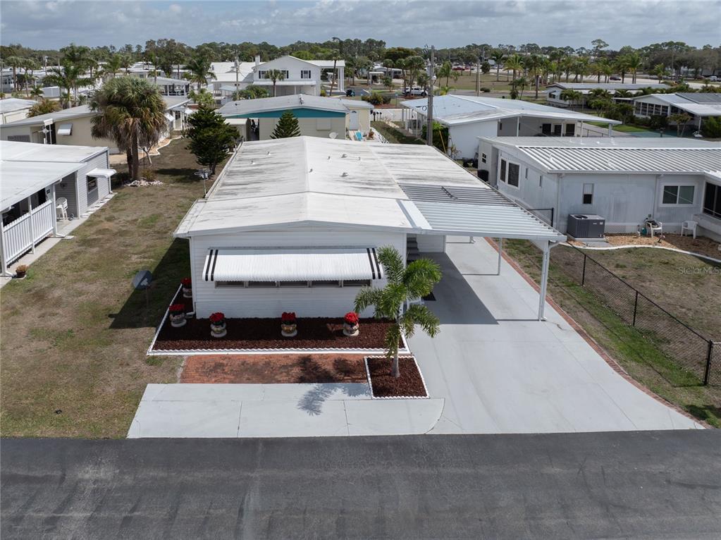 An aerial view of a white mobile home with a carport and landscaped front yard — 203 HARVEST LANE, NORTH FORT MYERS, FL