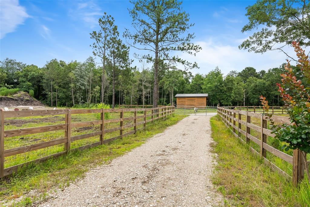 A gravel driveway leads through a wooden fence toward a small barn in a wooded area — 5747 RETREAT ROAD, KEYSTONE HEIGHTS, FL