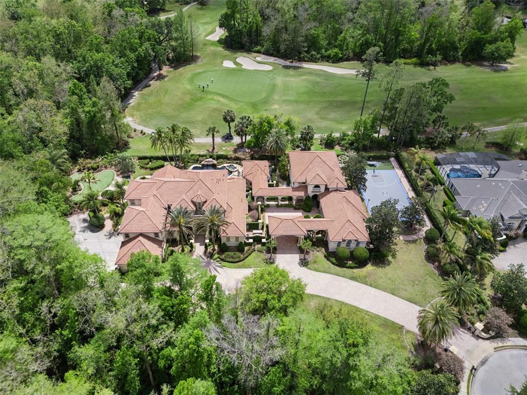 An aerial view shows a large house with a tile roof, pool, and basketball court — 3545 LEGACY HILLS COURT, LONGWOOD, FL