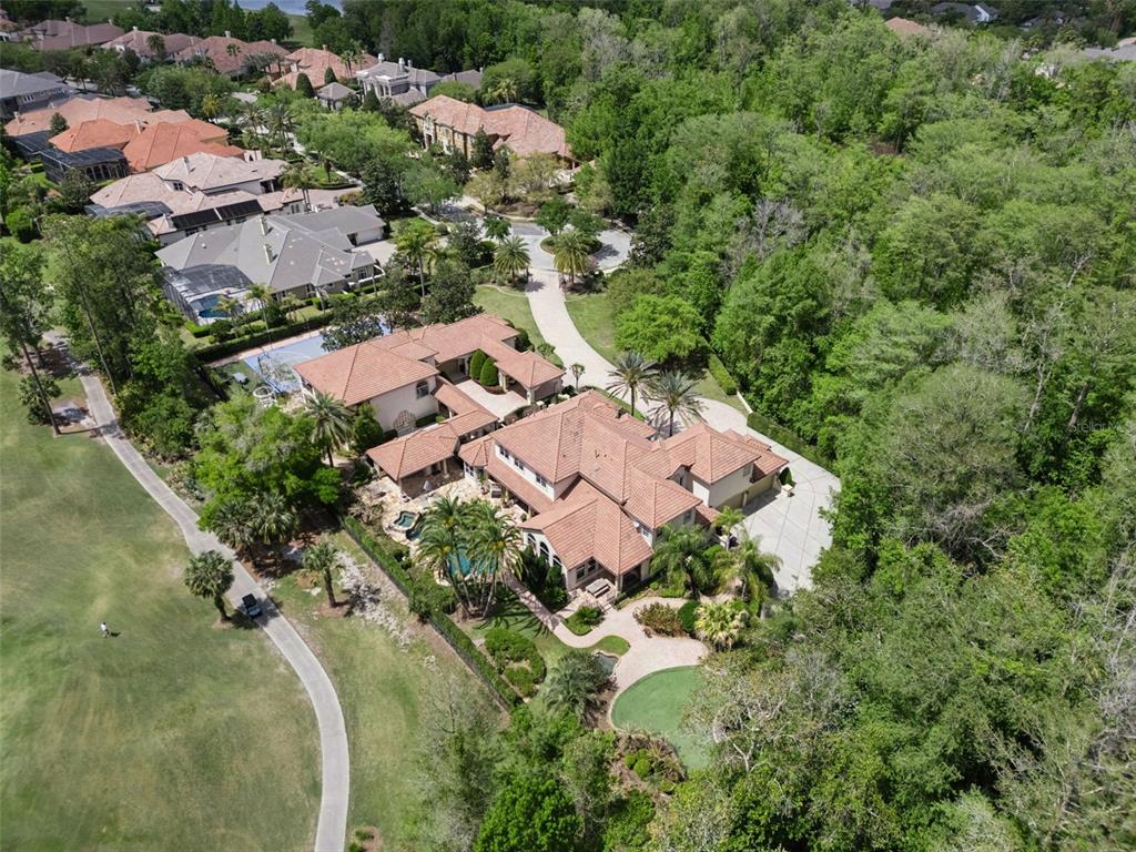 An aerial view shows a large house with a tile roof, pool, and putting green — 3545 LEGACY HILLS COURT, LONGWOOD, FL