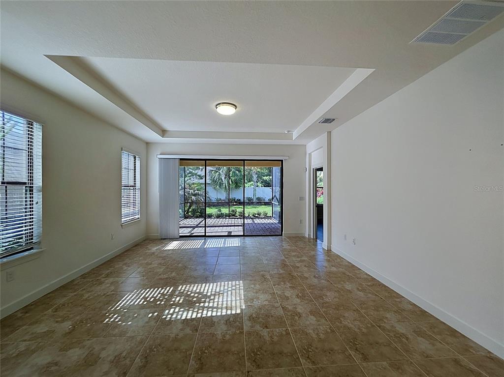A living room with tile floors, a tray ceiling, and sliding doors leading to a patio — 8335 ALBERATA VISTA DRIVE, TAMPA, FL