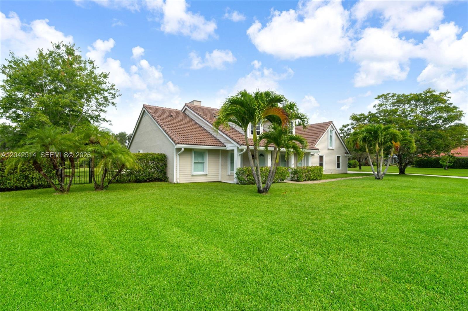 A single-story house with a tiled roof and palm trees sits on a grassy lawn — 5703 Lago Del Sol Dr, Lake Worth FL 33449, LAKE WORTH, FL
