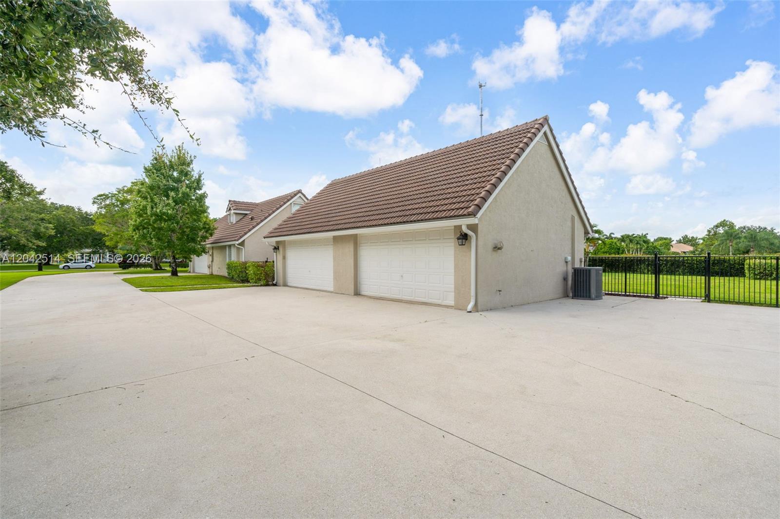 A two-car garage with a brown tiled roof sits at the end of a concrete driveway — 5703 Lago Del Sol Dr, Lake Worth FL 33449, LAKE WORTH, FL