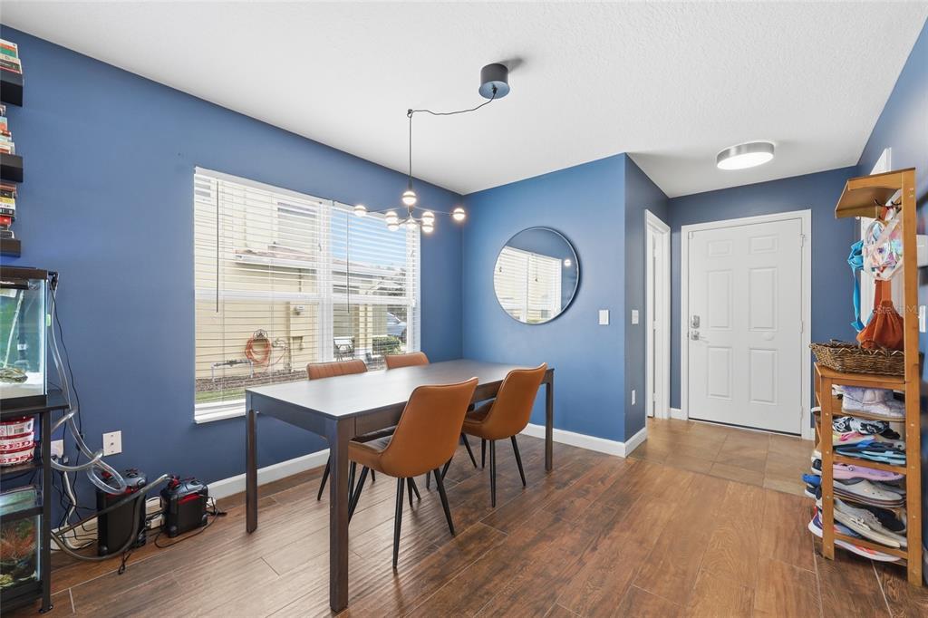 A dining room with blue walls, a dark wood table, and brown chairs — 3682 SOARING LANE, SANFORD, FL