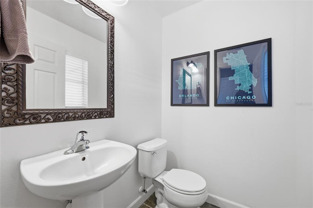 A half bathroom features a pedestal sink, a toilet, and two framed city map prints — 3682 SOARING LANE, SANFORD, FL
