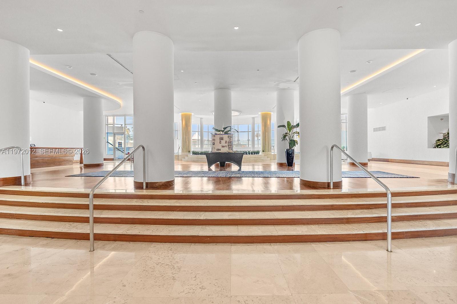 A spacious lobby features white columns, marble flooring, and a central set of stairs — 5161 Collins Ave # 910, Miami Beach FL 33140, MIAMI BEACH, FL