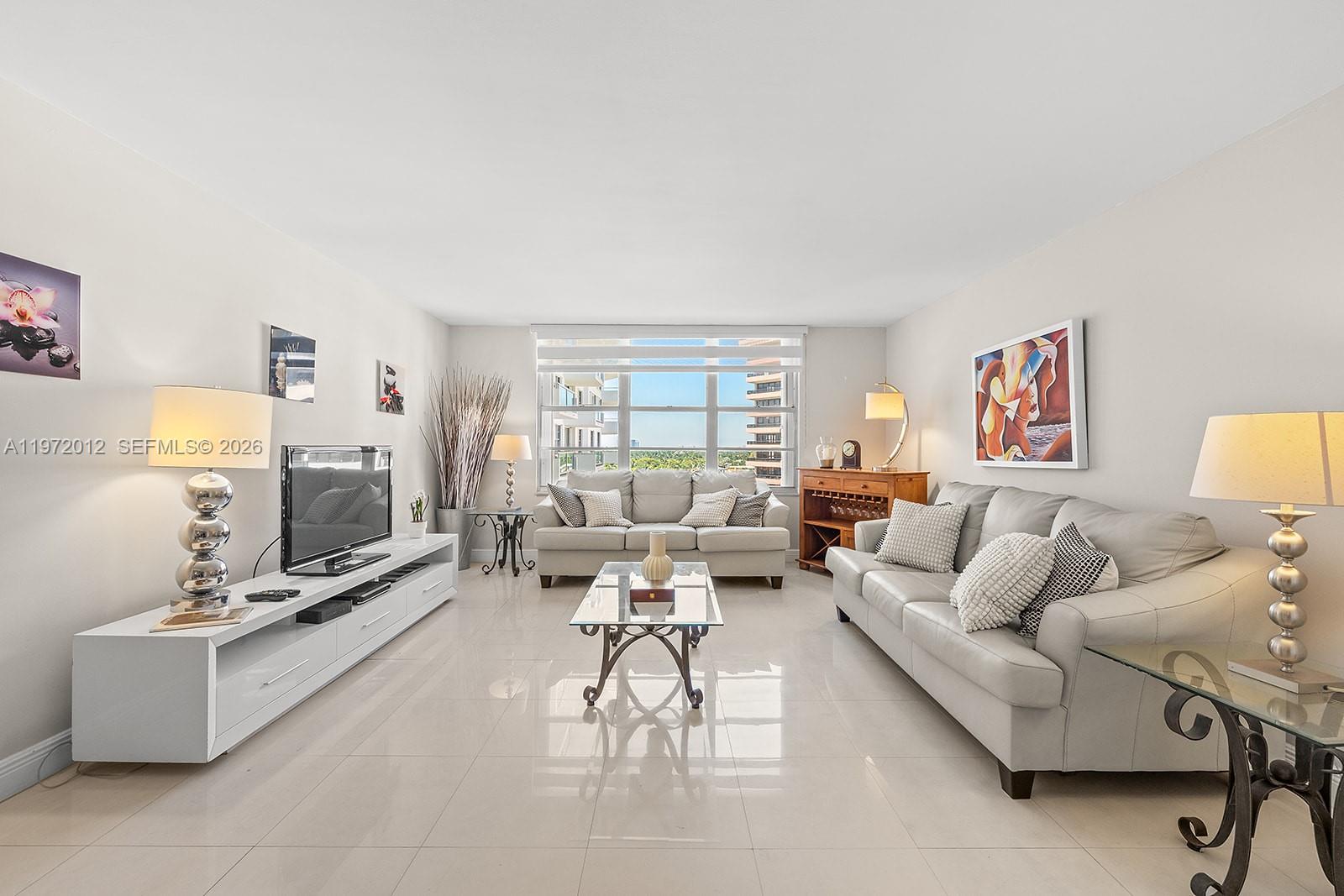 A bright living room features light tile floors, two gray sofas, and a large window — 5161 Collins Ave # 910, Miami Beach FL 33140, MIAMI BEACH, FL