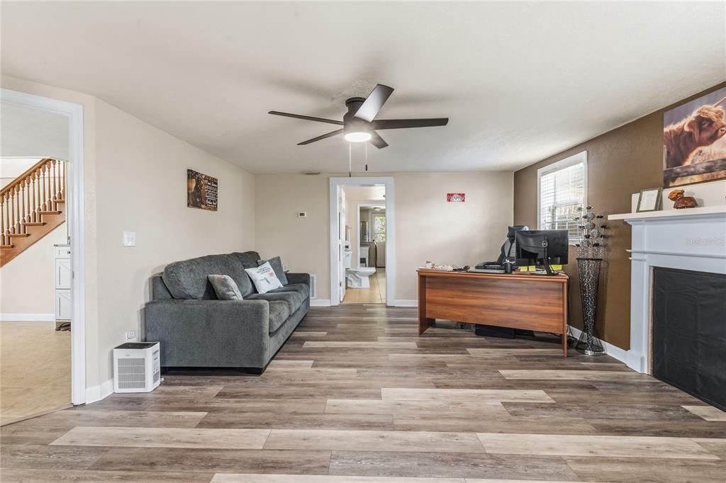 A living room features wood-look flooring, a gray sofa, a desk, and a fireplace — 1660 E MAIN STREET, BARTOW, FL