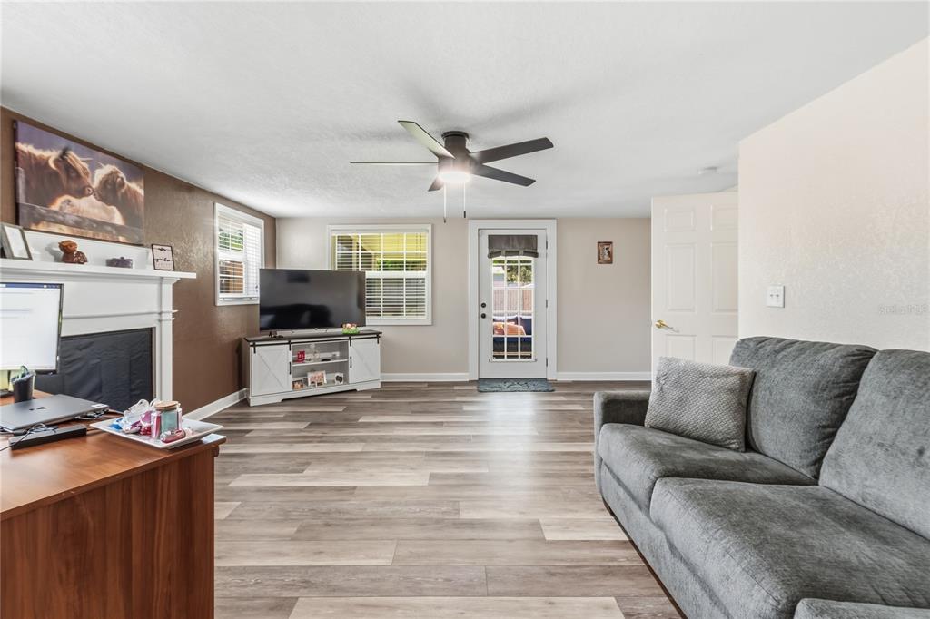 A living room features wood-look flooring, a ceiling fan, a fireplace, and a glass-paneled door — 1660 E MAIN STREET, BARTOW, FL