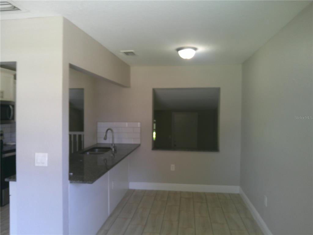 A kitchen with a granite breakfast bar, white subway tile backsplash, and light wood-look flooring — 1241 NICHOLSON STREET, CLEARWATER, FL