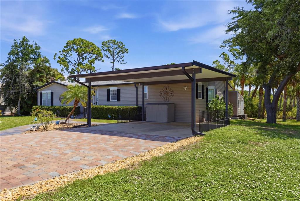 A single-story house features a paved driveway leading to a covered carport and lawn — 9158 PINEHAVEN WAY, ENGLEWOOD, FL