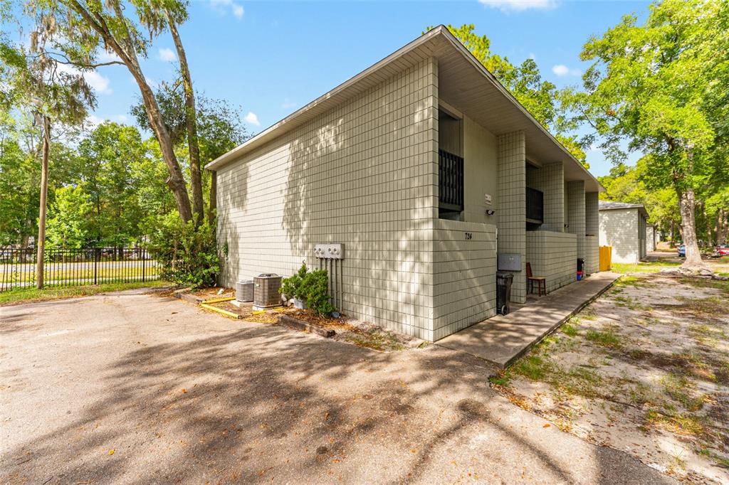 A two-story apartment building with light-colored block siding and an adjacent paved parking area — 724 SW 68TH TERRACE, GAINESVILLE, FL