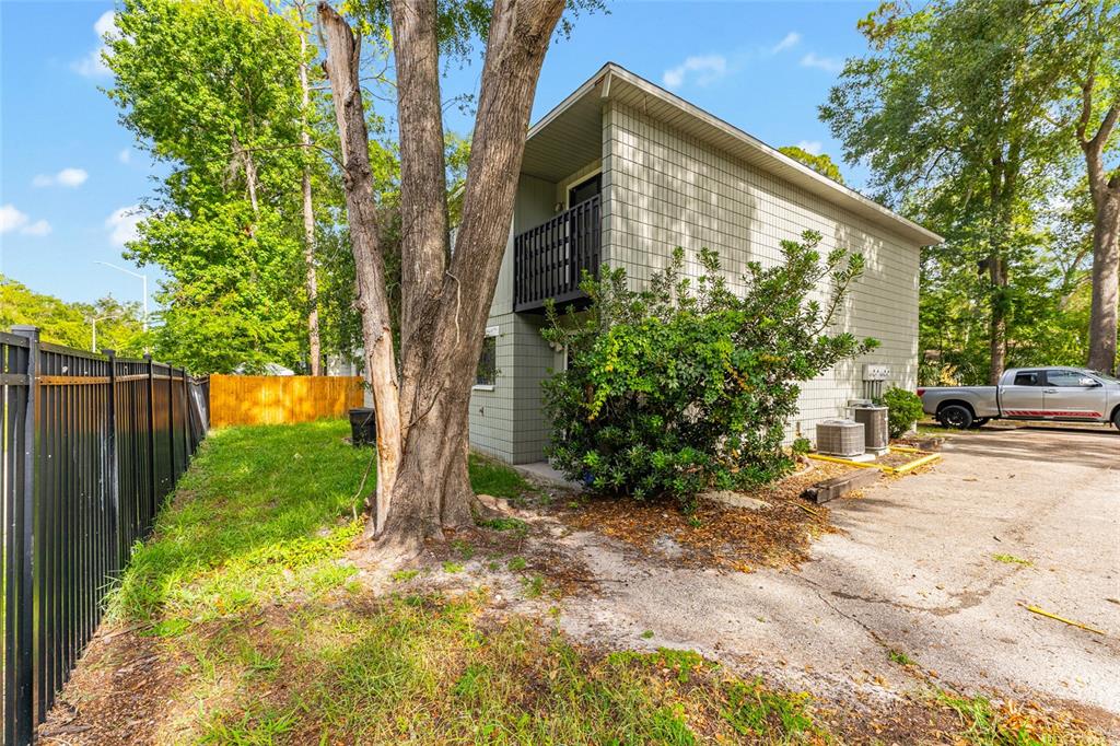 The exterior of a two-story building features light-colored siding, a small balcony, and surrounding trees — 724 SW 68TH TERRACE, GAINESVILLE, FL
