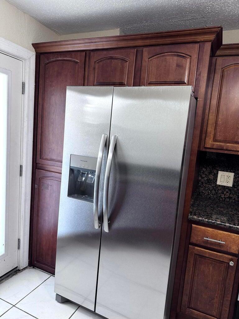 A stainless steel refrigerator is positioned between dark wood cabinetry in a kitchen — 6200 S Falls Cir Drive # 310, Lauderhill FL 33319, LAUDERHILL, FL