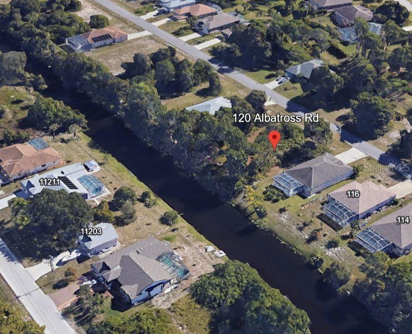 This aerial view shows a residential lot with trees situated along a canal — 120 ALBATROSS ROAD, ROTONDA WEST, FL