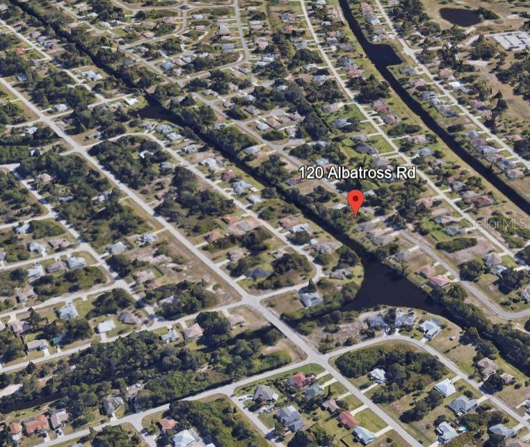 An aerial view of a residential neighborhood with houses situated along a canal — 120 ALBATROSS ROAD, ROTONDA WEST, FL