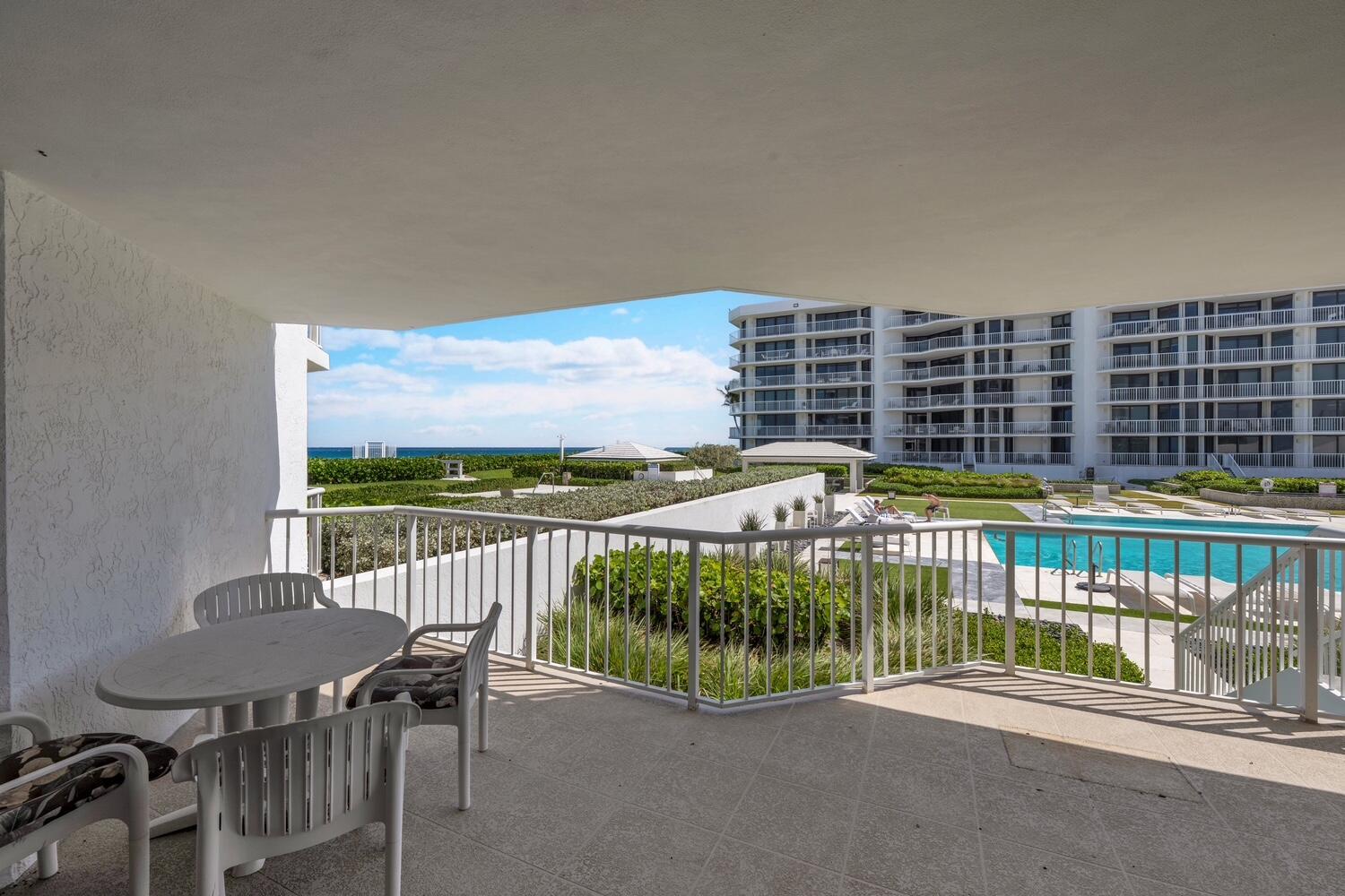 A covered balcony with a dining set overlooks a swimming pool and the ocean — 3170 S Ocean Boulevard # 201n, Palm Beach FL 33480, PALM BEACH, FL