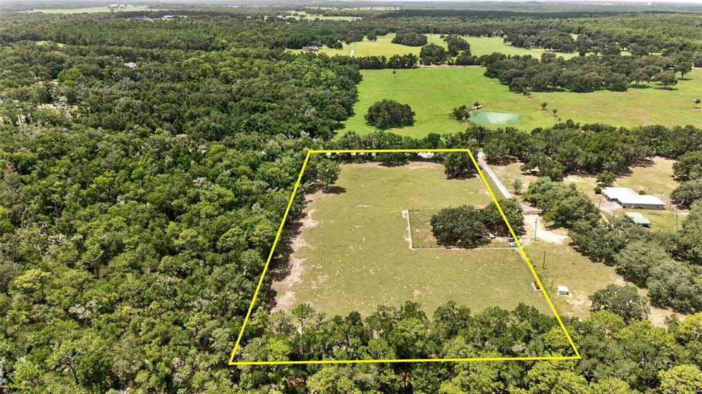 An aerial view shows a rectangular, fenced pasture surrounded by dense forest and trees — 2741 E STAGE COACH TRAIL, INVERNESS, FL