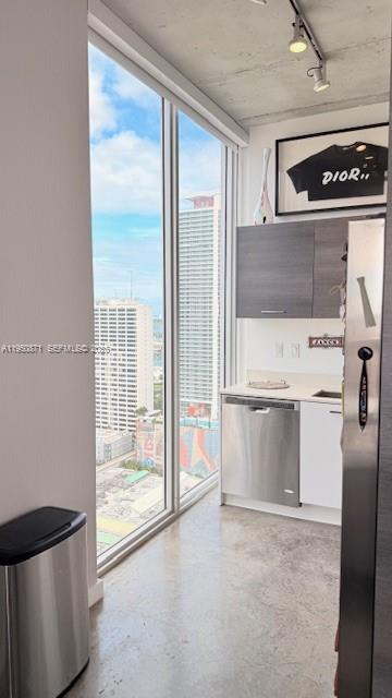 A modern kitchen with concrete floors, stainless steel appliances, and floor-to-ceiling windows overlooking city buildings — 151 SE 1st St # 3010, Miami FL 33131, MIAMI, FL