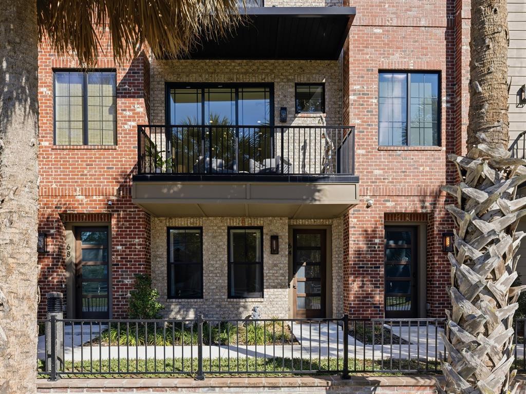 A multi-story brick townhouse features a second-floor balcony, black-framed windows, and a metal fence — 64 N PARK AVENUE, WINTER GARDEN, FL
