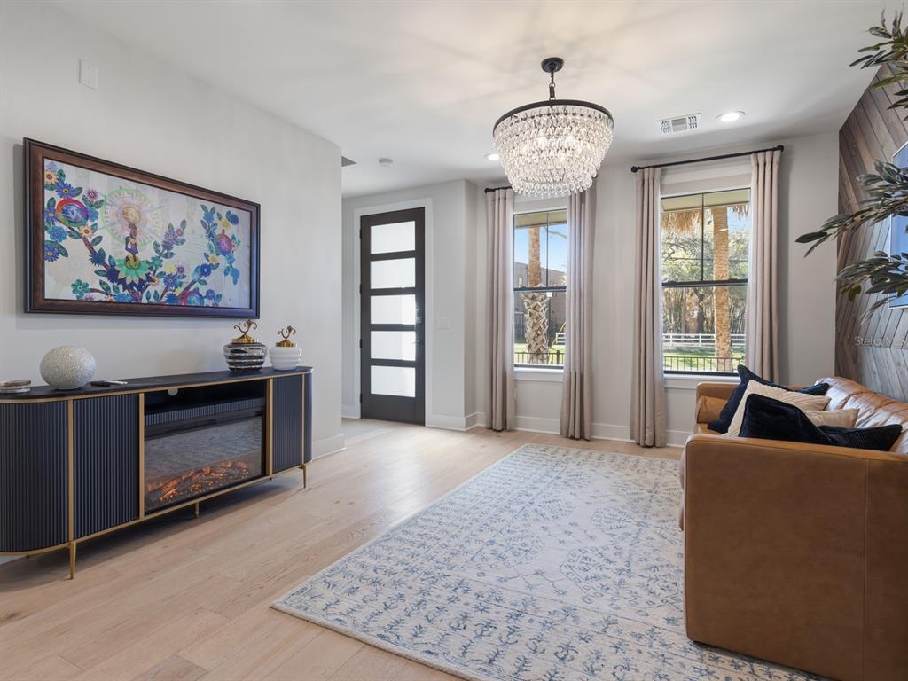 A living room features a fireplace console, a leather sofa, and a crystal chandelier — 64 N PARK AVENUE, WINTER GARDEN, FL