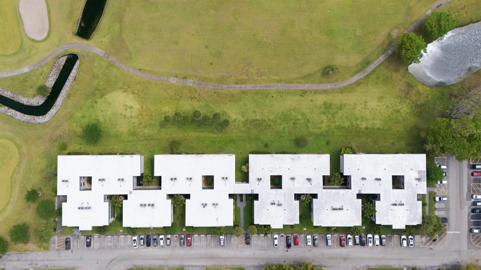 An aerial view shows a multi-unit residential building with a parking lot and grassy lawn — 563 Piedmont L, Delray Beach FL 33484, DELRAY BEACH, FL