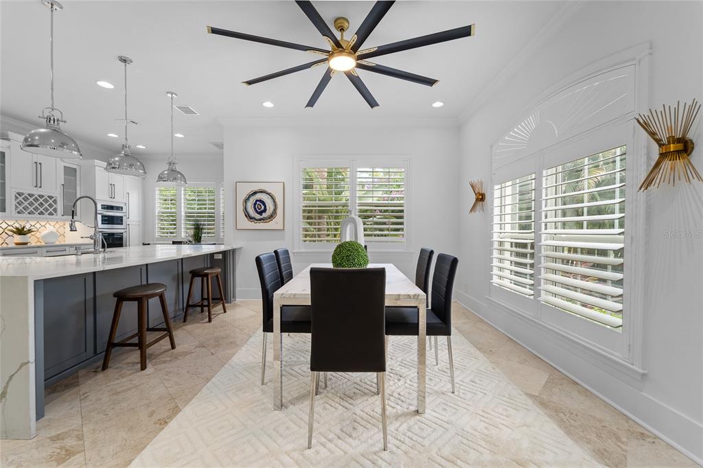 A dining area with a modern ceiling fan, white table, and black chairs near a kitchen — 4802 W BEACHWAY DRIVE, TAMPA, FL