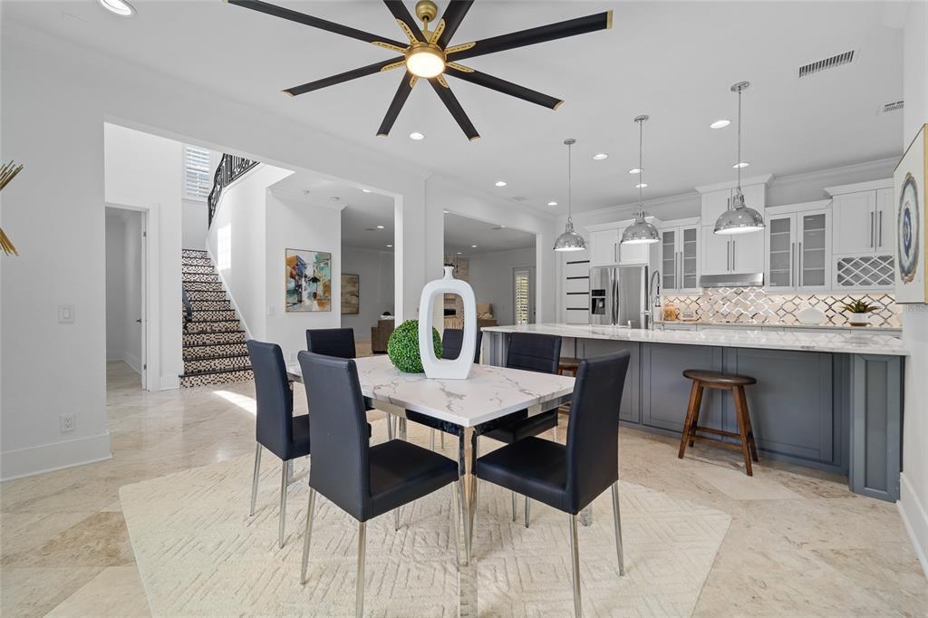 A dining area with a marble table and black chairs sits before a modern kitchen — 4802 W BEACHWAY DRIVE, TAMPA, FL