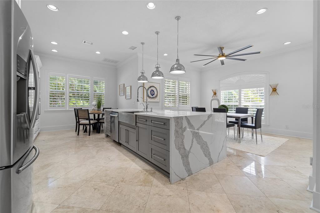 A kitchen with a large marble-topped island, gray cabinetry, and a dining area — 4802 W BEACHWAY DRIVE, TAMPA, FL