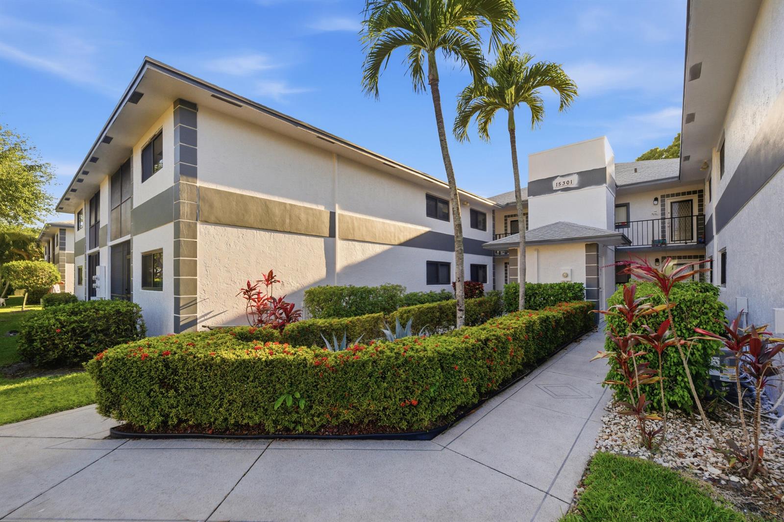 A two-story apartment building exterior features white stucco walls, gray trim, and landscaped hedges — 15301 Pembridge Avenue # 44, Delray Beach FL 33484, DELRAY BEACH, FL