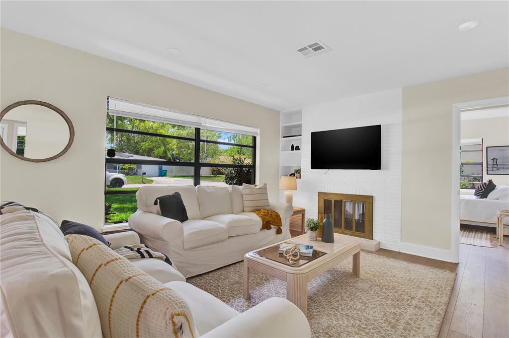 A living room features a white brick fireplace, a sofa, and a coffee table — 1608 OTTAWA ROAD, CLEARWATER, FL