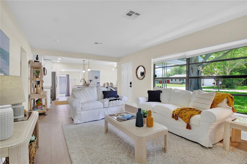 A bright living room features white sofas, a coffee table, and a large window view — 1608 OTTAWA ROAD, CLEARWATER, FL