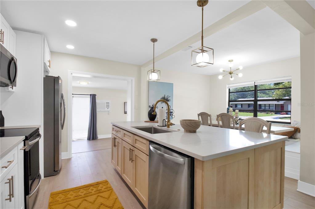 A kitchen with a light wood island, white cabinets, stainless steel appliances, and a dining area — 1608 OTTAWA ROAD, CLEARWATER, FL
