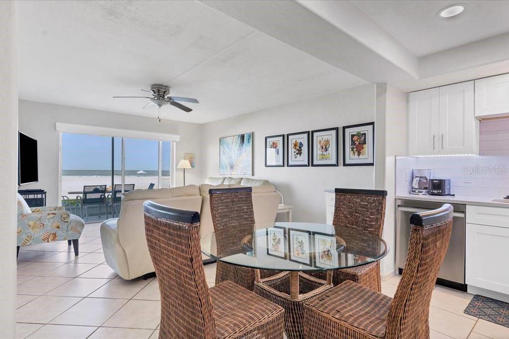 A dining area with a glass table and wicker chairs overlooks a beach and ocean — 6154 MIDNIGHT PASS ROAD UNIT 103, SARASOTA, FL