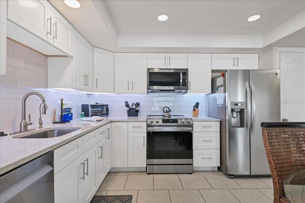 A kitchen with white cabinets, stainless steel appliances, and light-colored countertops — 6154 MIDNIGHT PASS ROAD UNIT 103, SARASOTA, FL
