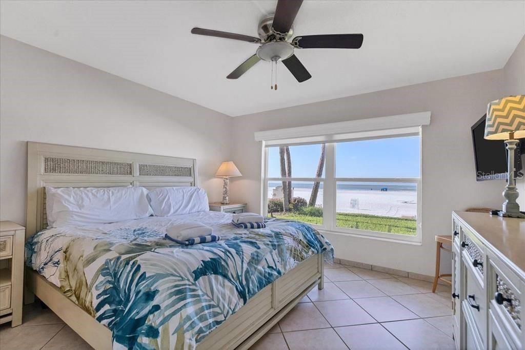 A bedroom with a king bed, tiled floors, and a large window overlooking the beach — 6154 MIDNIGHT PASS ROAD UNIT 103, SARASOTA, FL