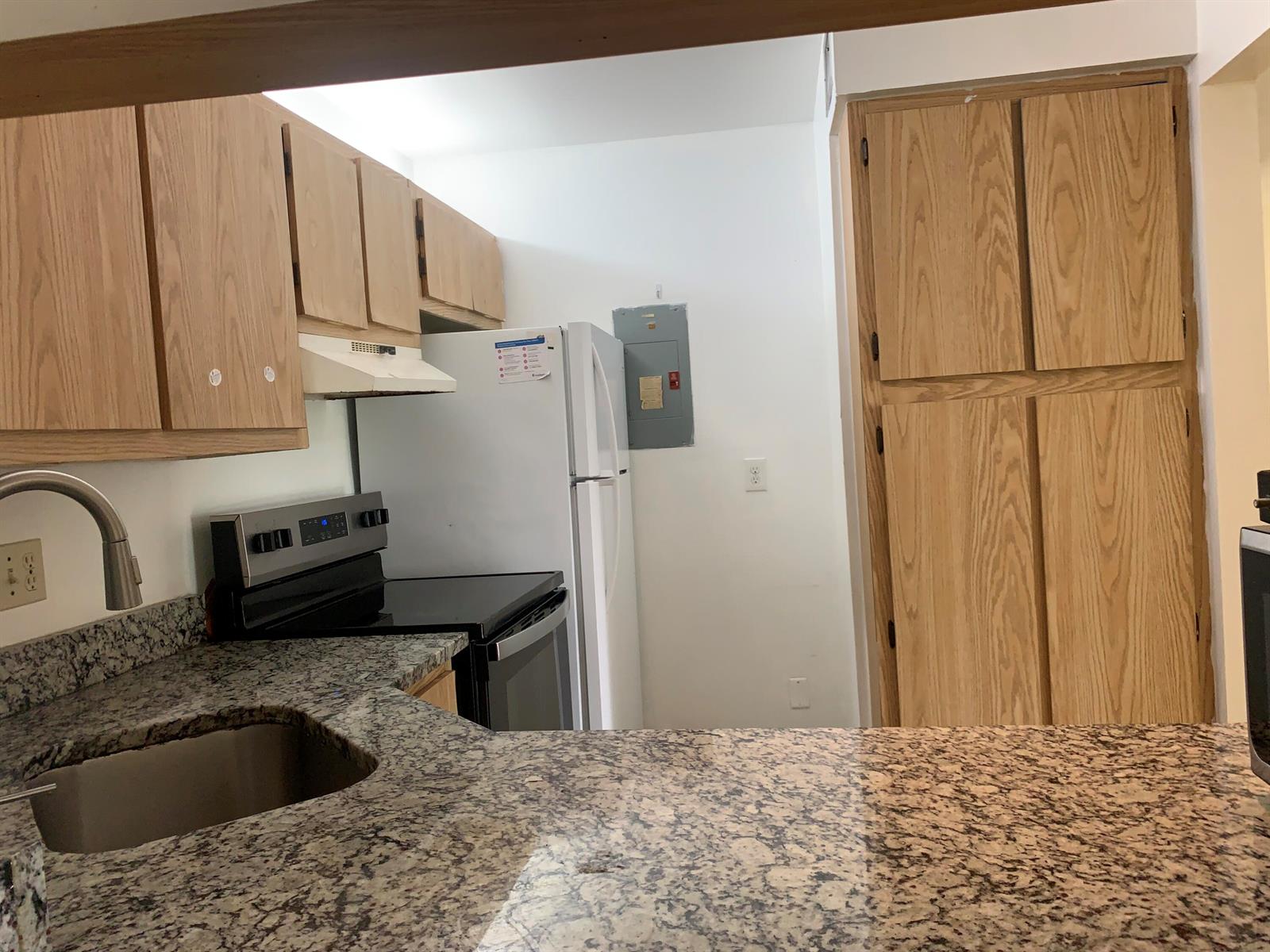 A kitchen features granite countertops, light wood cabinets, a white refrigerator, and a stainless steel stove — 1113 Green Pine Boulevard # B3, West Palm Beach FL 33409, WEST PALM BEACH, FL