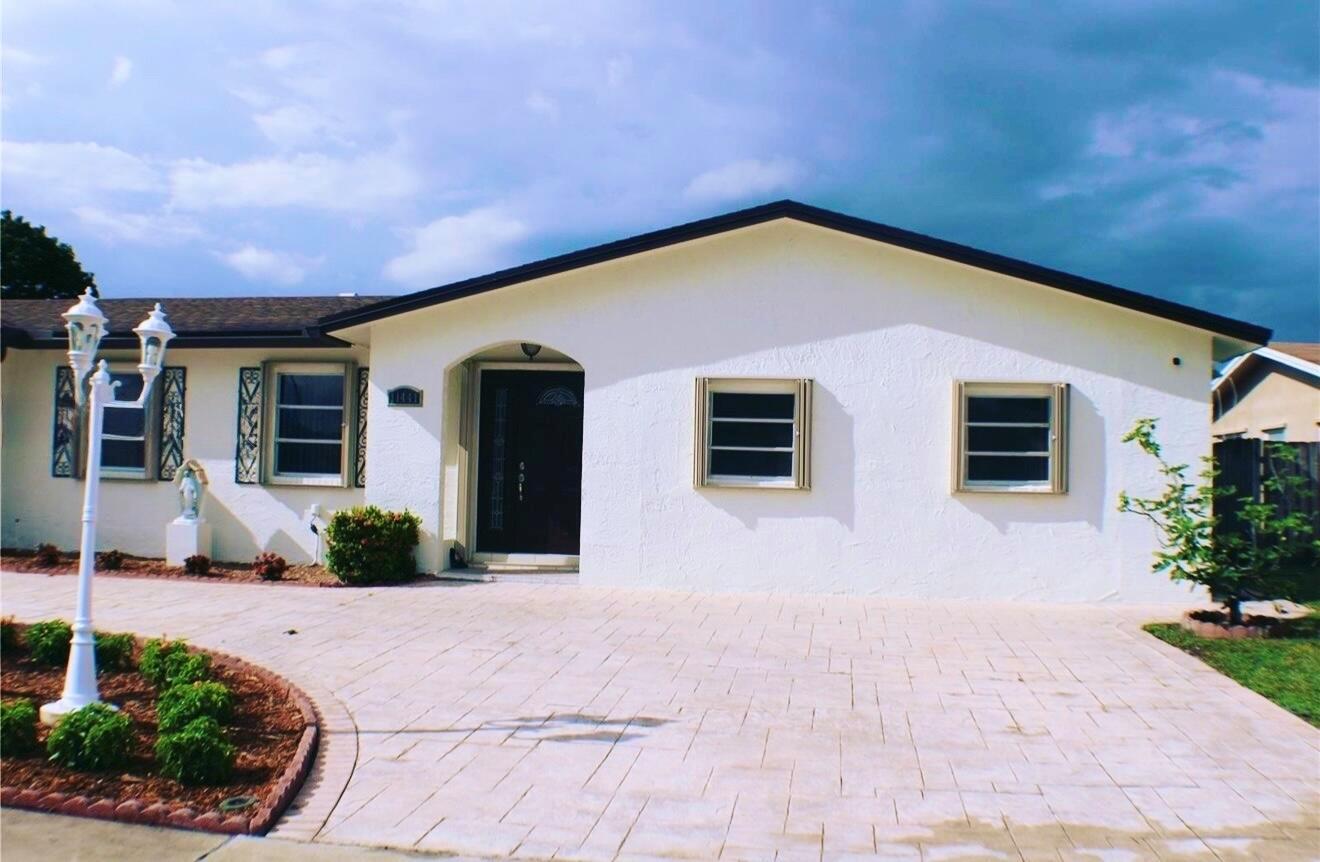 A single-story white house with a paved driveway, dark front door, and louvered windows — 11441 NW 29th Manor, Sunrise FL 33323, SUNRISE, FL
