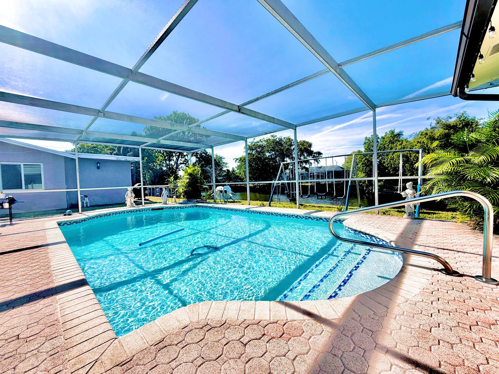 A screened-in swimming pool with a paver deck overlooks a canal and backyard — 11441 NW 29th Manor, Sunrise FL 33323, SUNRISE, FL