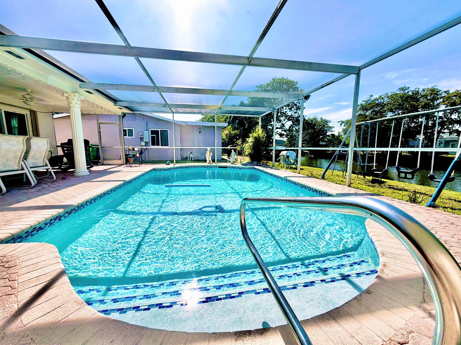 A screened-in swimming pool with a metal handrail and a patio area overlooking a canal — 11441 NW 29th Manor, Sunrise FL 33323, SUNRISE, FL