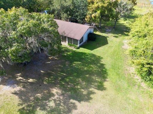 An aerial view shows a house with a brown roof surrounded by trees and grass — 4705 KISSIMMEE PARK ROAD, ST CLOUD, FL
