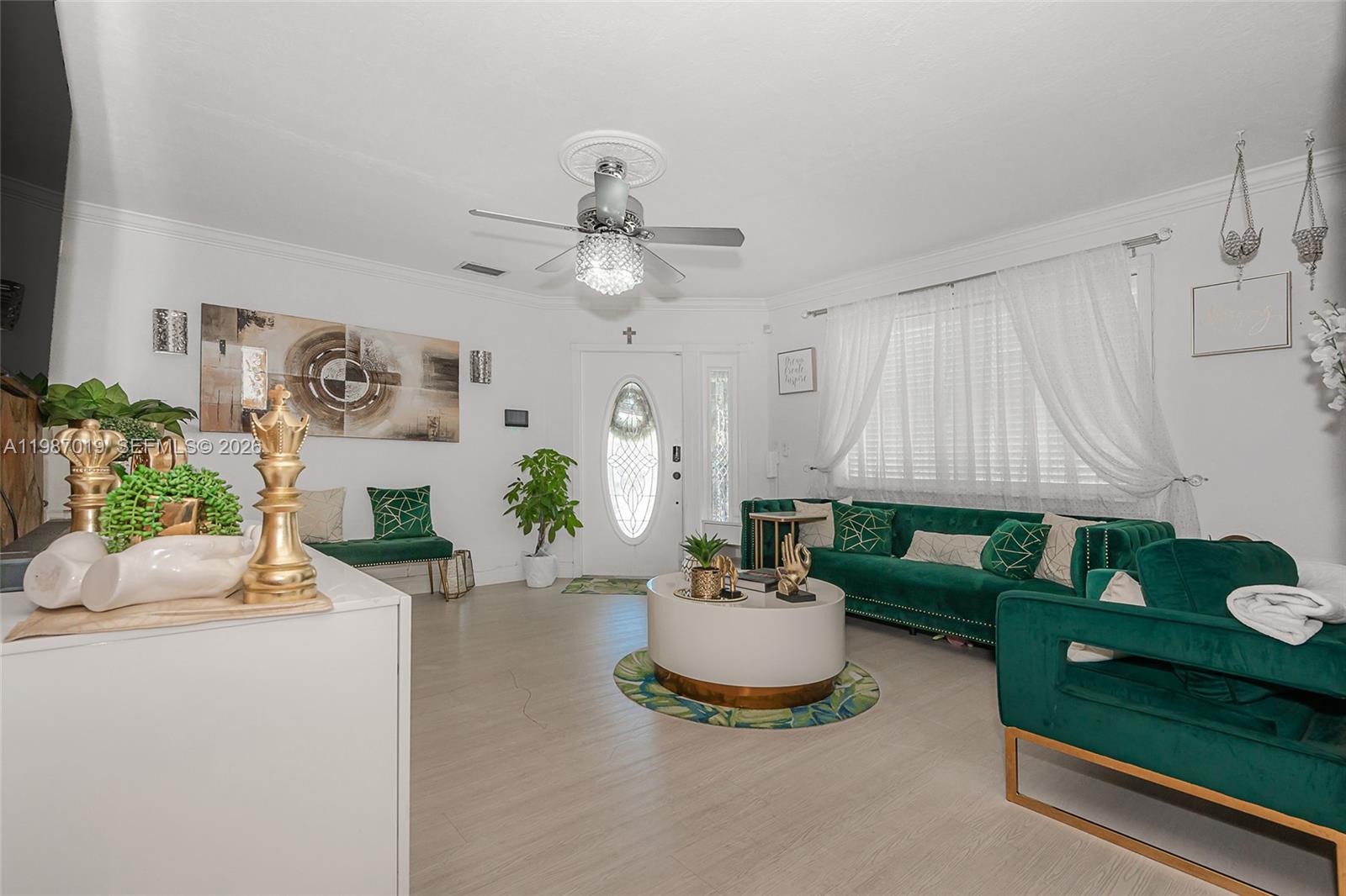 A living room features white walls, light wood-look flooring, and emerald green velvet furniture — 7171 Sheridan St, Hollywood FL 33024, HOLLYWOOD, FL
