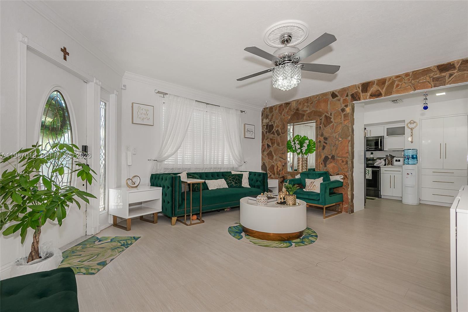A living room features a green velvet sofa, stone accent wall, and a ceiling fan — 7171 Sheridan St, Hollywood FL 33024, HOLLYWOOD, FL