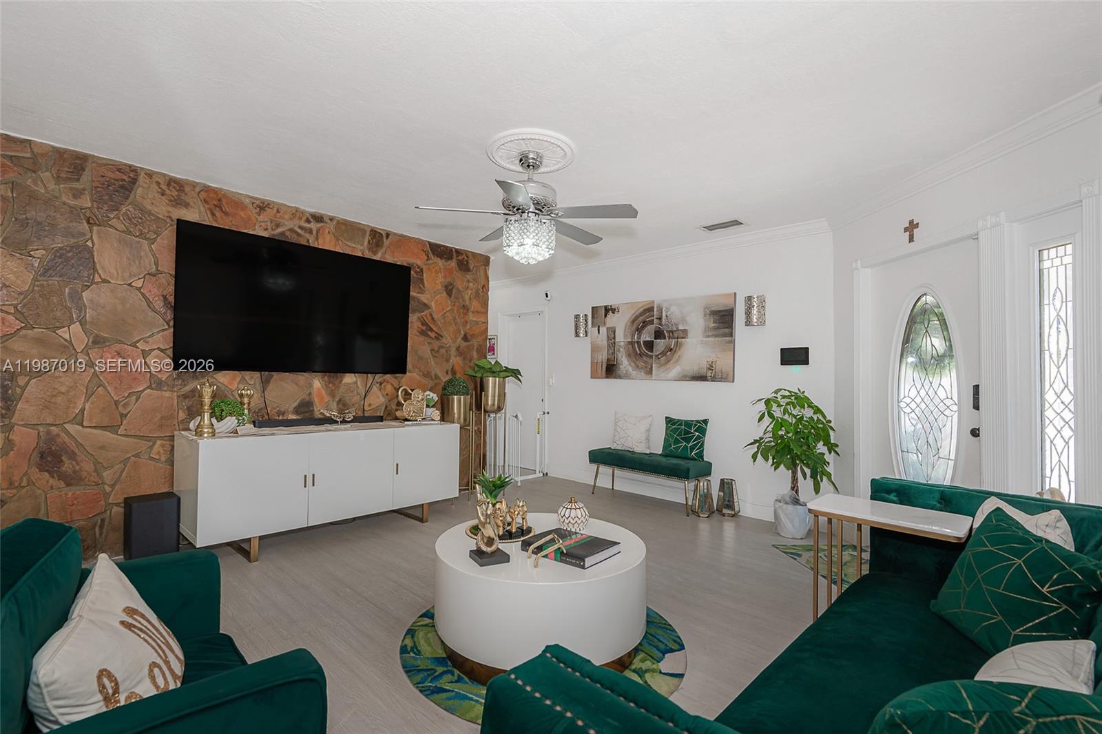 A living room features a stone accent wall, green velvet furniture, and a white console — 7171 Sheridan St, Hollywood FL 33024, HOLLYWOOD, FL