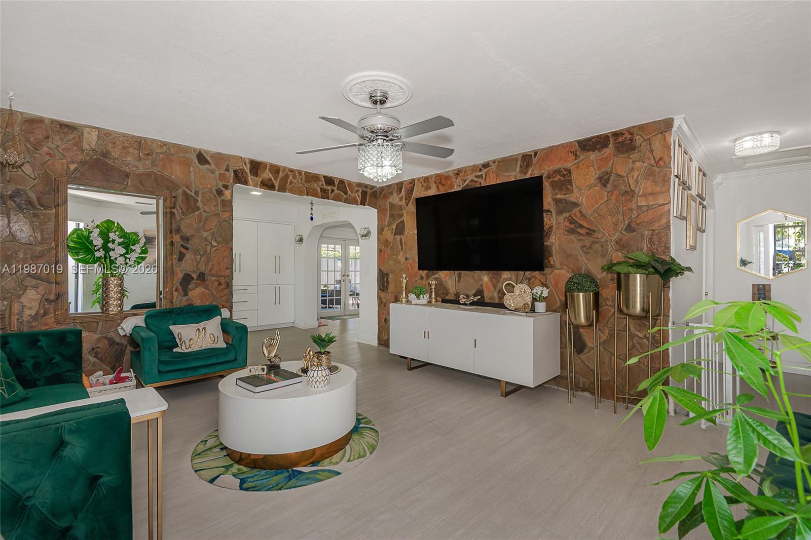 A living room features a stone accent wall, a white media console, and green furniture — 7171 Sheridan St, Hollywood FL 33024, HOLLYWOOD, FL